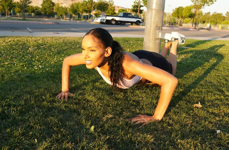 girl doing pushups on her knees in the park 