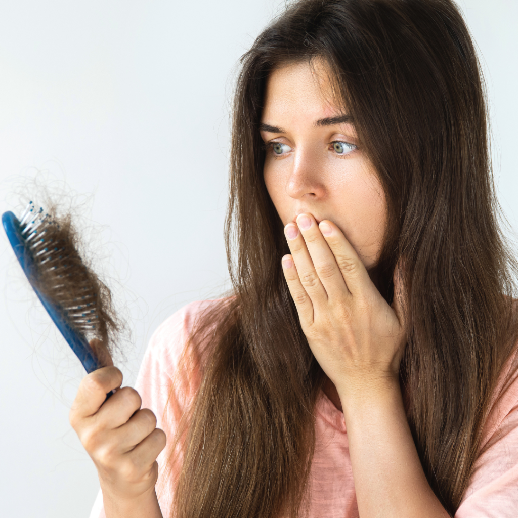 woman looking at hair brush with hair strands on it