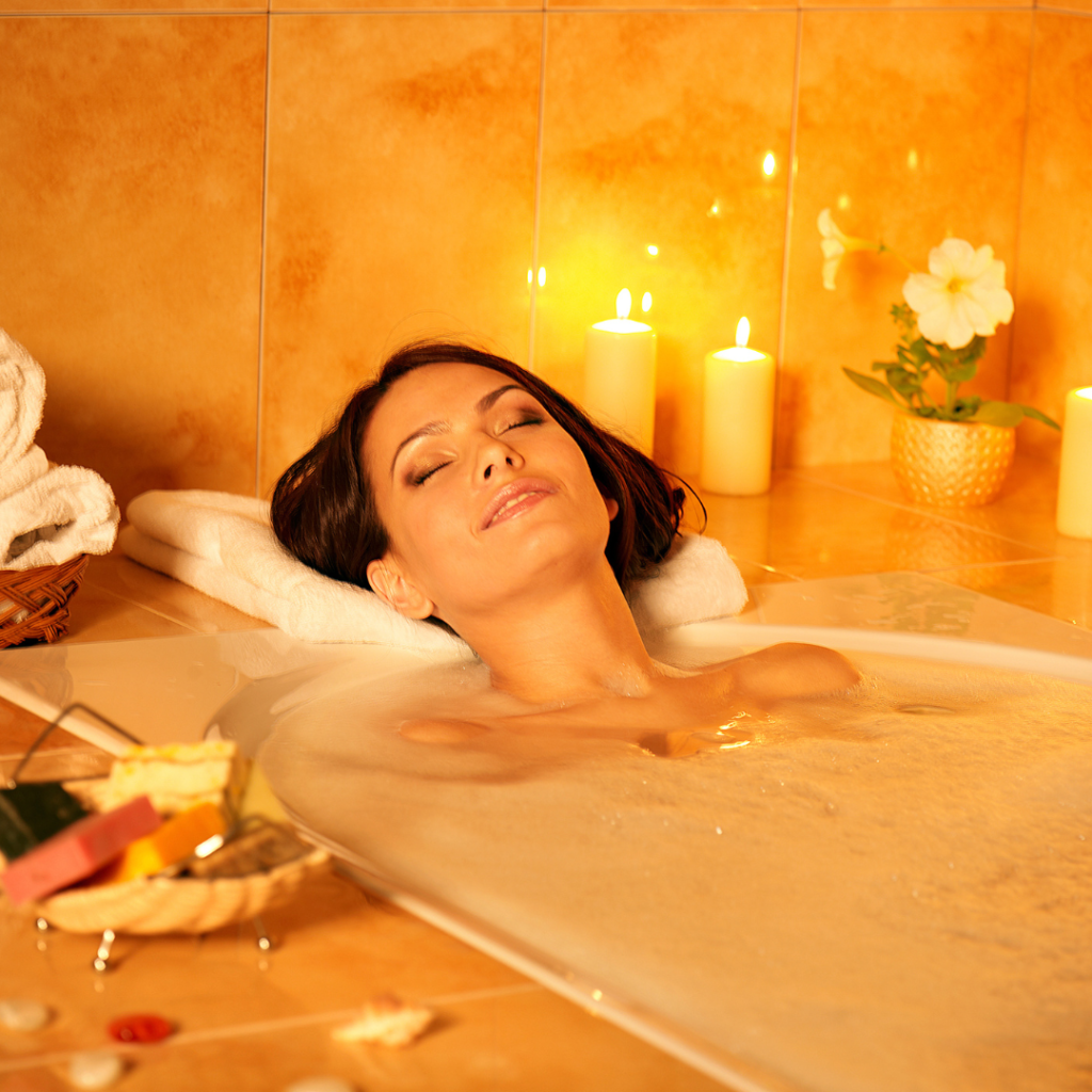 woman taking a relaxing bath surrounded by candles